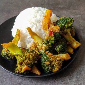 Asian style broccoli in garlic sauce served with rice on a black plate