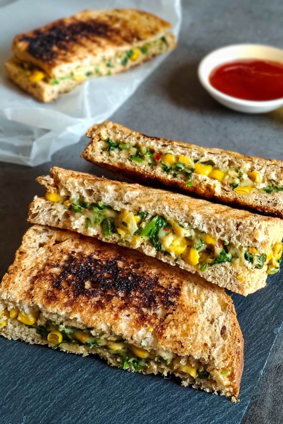 four spinach corn sandwiches with a bowl of ketchup in the background.