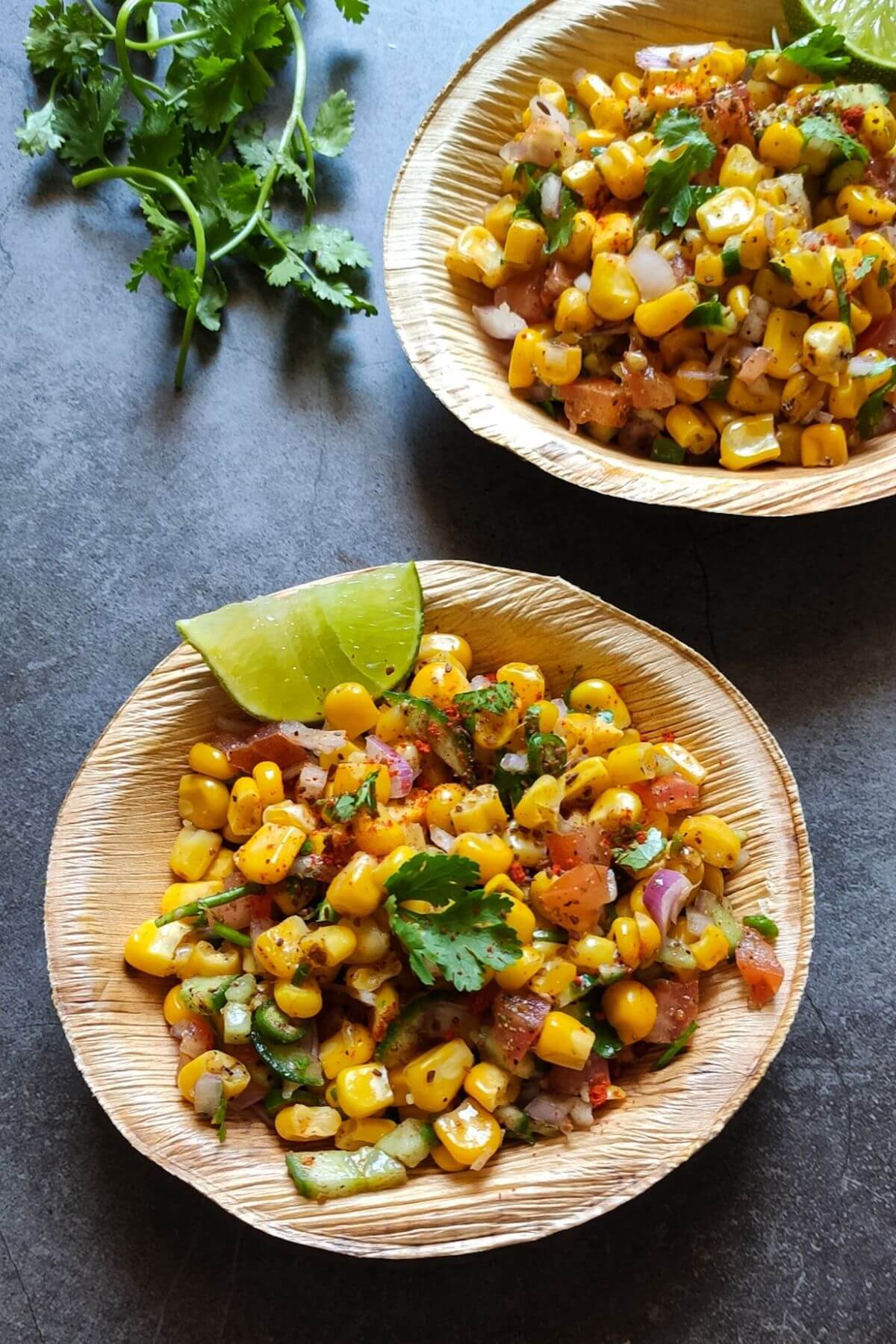 two bowls of spicy corn salad with a bunch of cilantro.