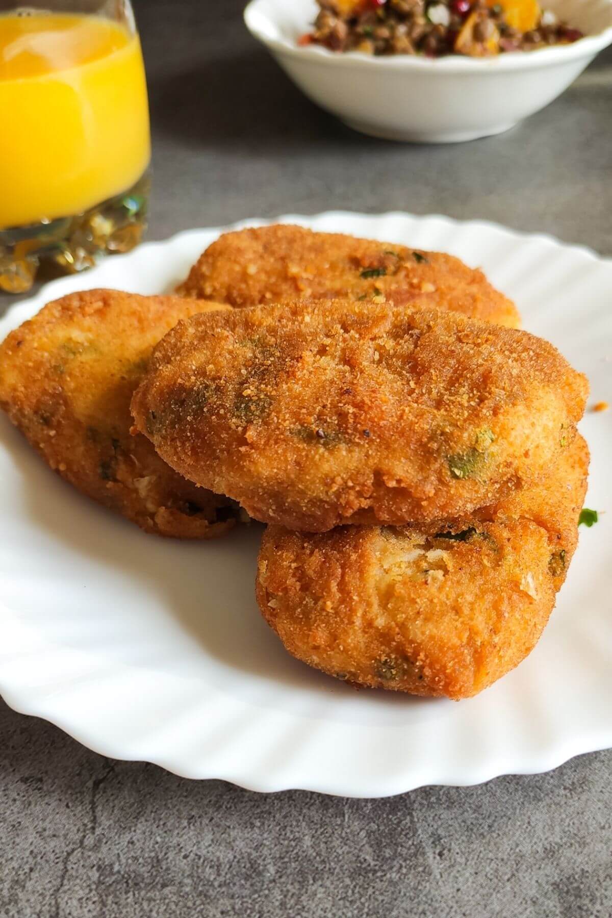 chickpea cutlets on a white plate with a glass of juice.