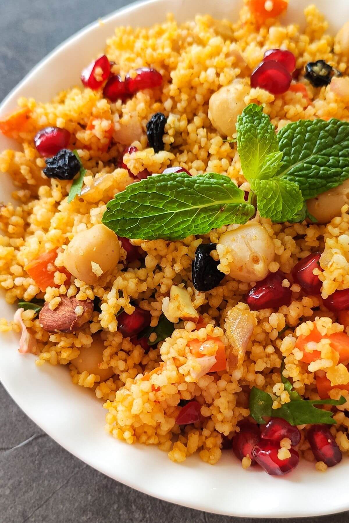 Couscous salad garnished with mint leaves in a white bowl
