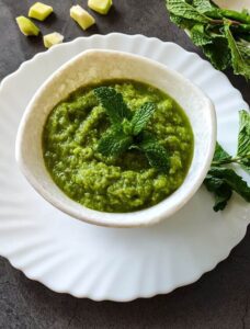 raw mango chutney in a white bowl garnished with mint leaves