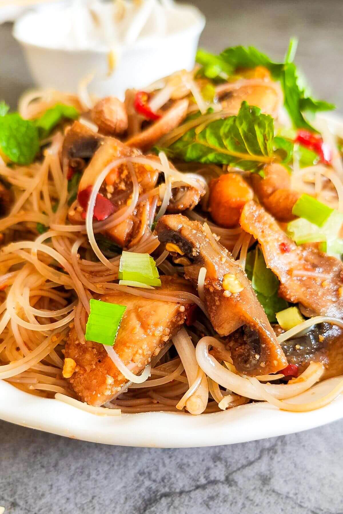 Thai vermicelli noodle salad garnished with fresh herbs served in a bowl.