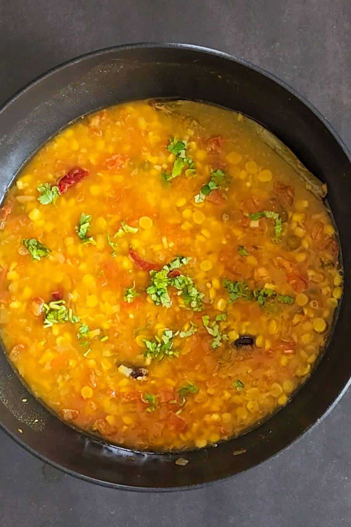 cooked chana dal garnished with chopped cilantro in a cooking pot.