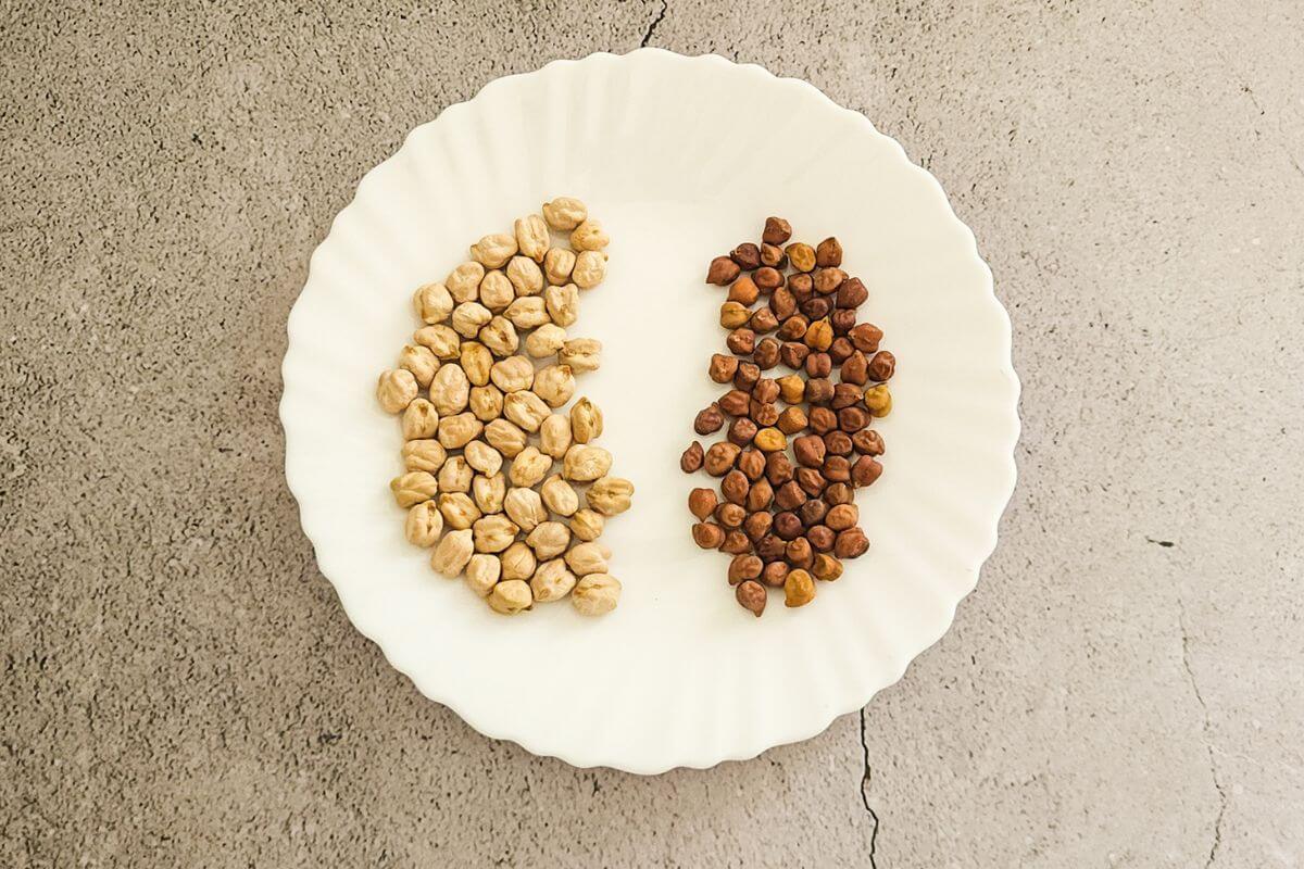 Regular white chickpeas and black chickpeas kept side by side on a white plate.