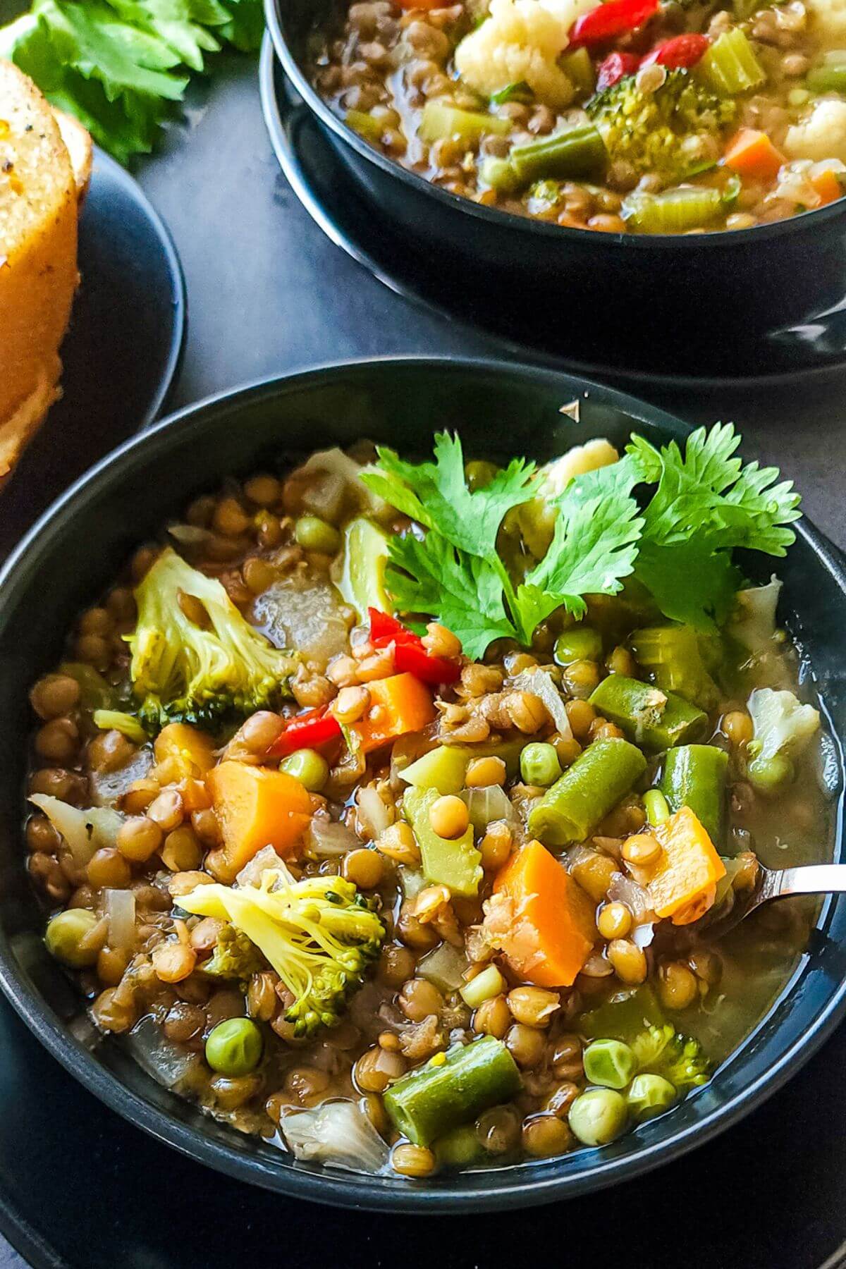Two bowls of lentils soup with vegetables.