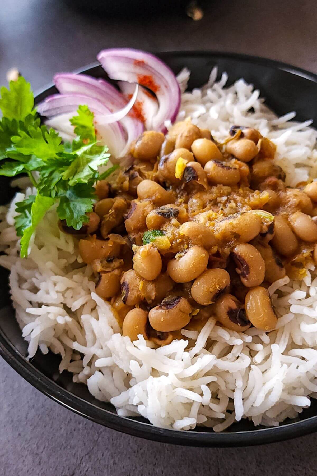 Indian black eyed beans curry, rice, and salad in a bowl.
