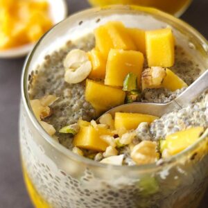 Close up shot of mango chia seeds pudding in a glass with a spoon.