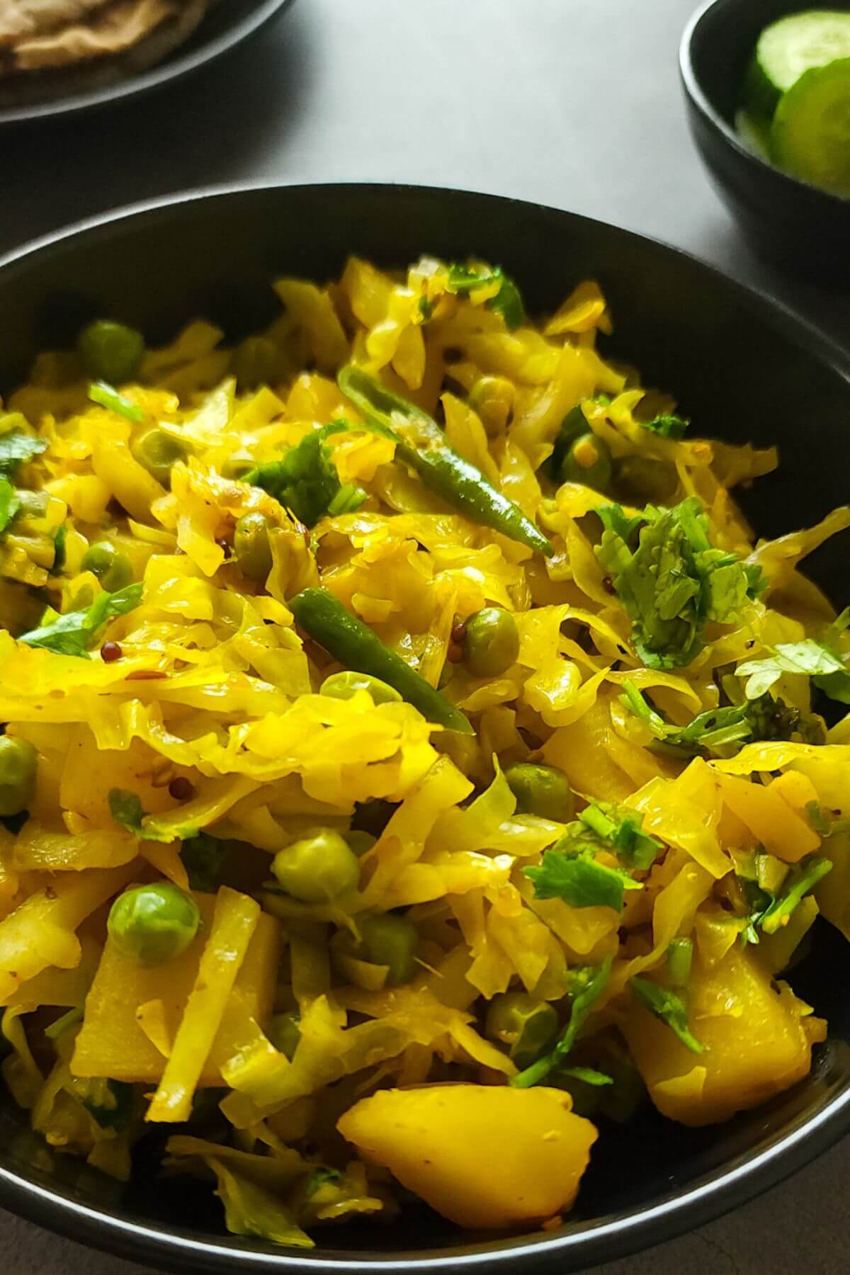 Cabbage sabzi in a bowl with salad in the background.