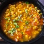 Chana dal garnished with chopped cilantro served in a black bowl.
