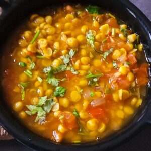 Chana dal garnished with chopped cilantro served in a black bowl.