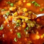 Frozen vegetable soup garnished with chopped cilantro in a bowl with a spoon.