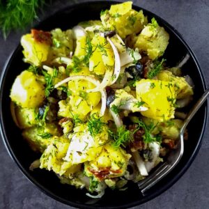 Greek potato salad in a black bowl with a fork.