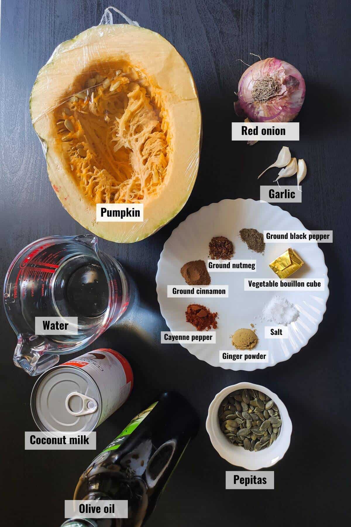 Ingredients for vegan pumpkin soup kept on a black surface and labelled.