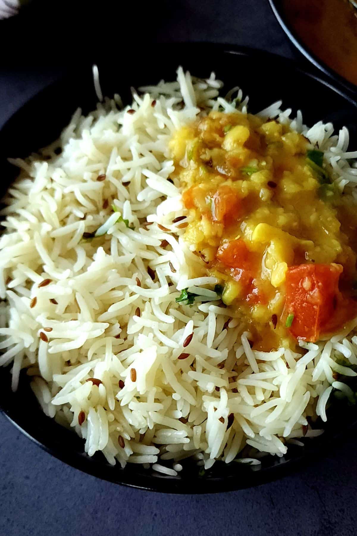 Jeera rice and dal served in a black bowl.