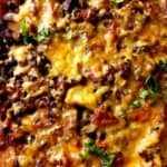 Close up shot of cheesy lentil casserole garnished with chopped parsley.