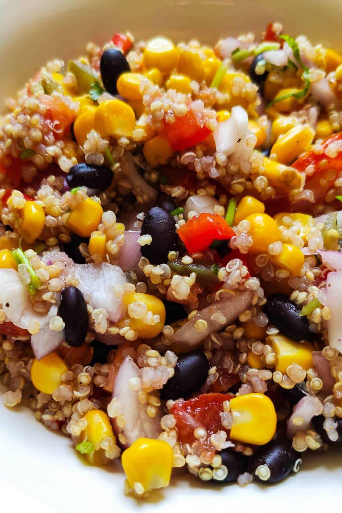 Mexican quinoa salad with sweet corn kernels, black beans, onions, and bell peppers.