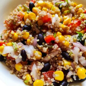 Mexican quinoa salad served in a white bowl kept on a blue table napkin.
