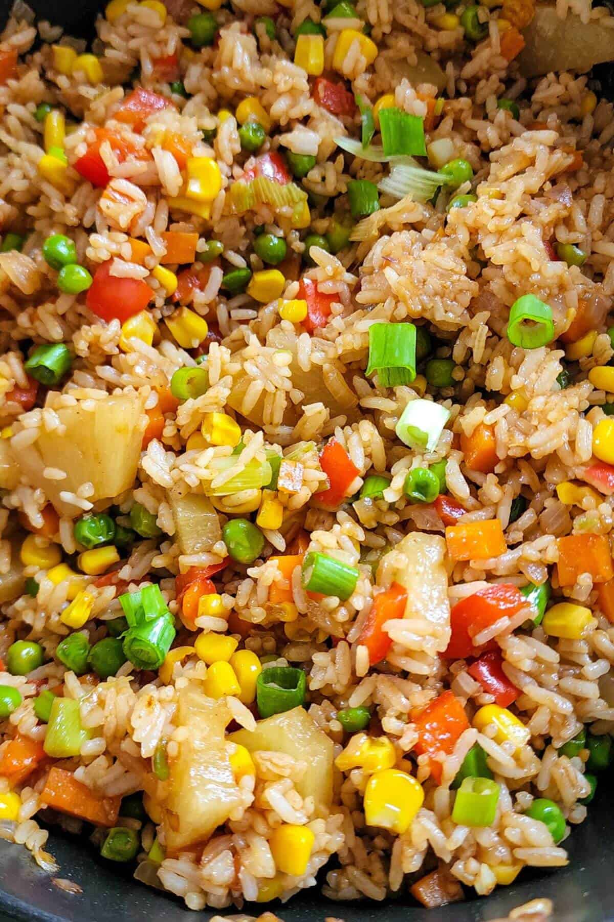 Pineapple fried rice with vegetables in a wok.