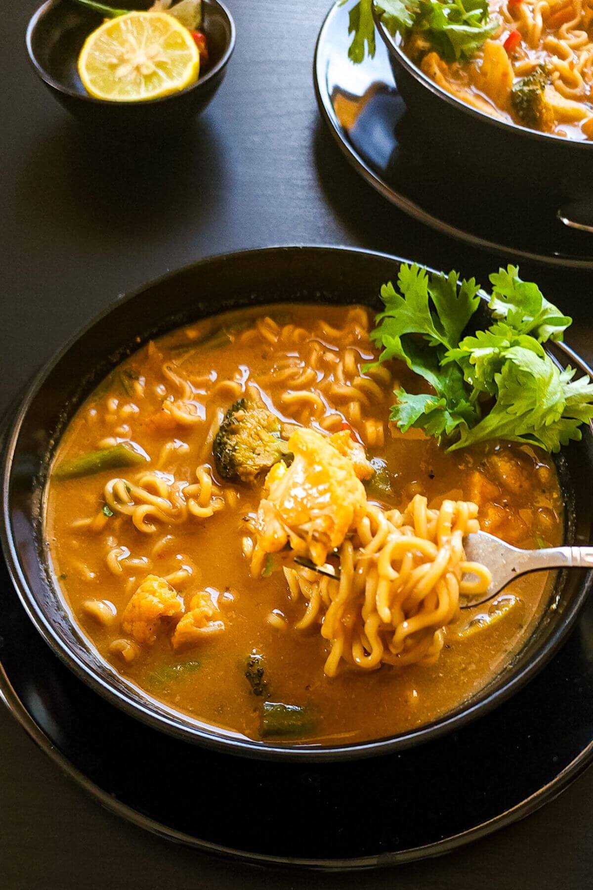 Two bowls of Thai coconut curry noodle soup.