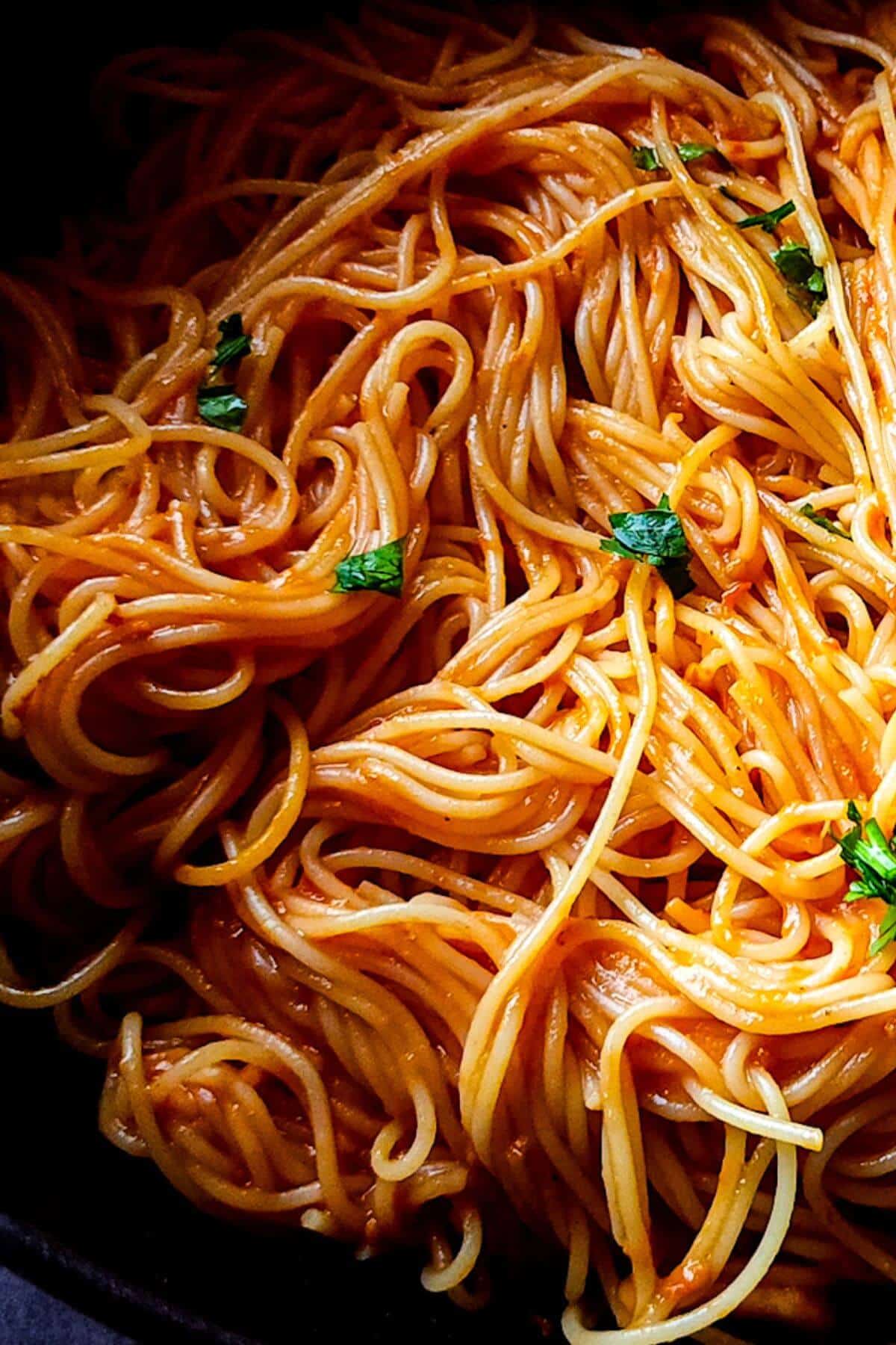 Tomato spaghetti garnished with chopped parsley.