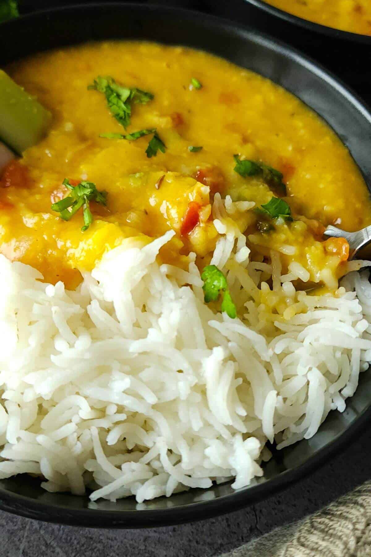 Moong malka dal with rice served in a black bowl.