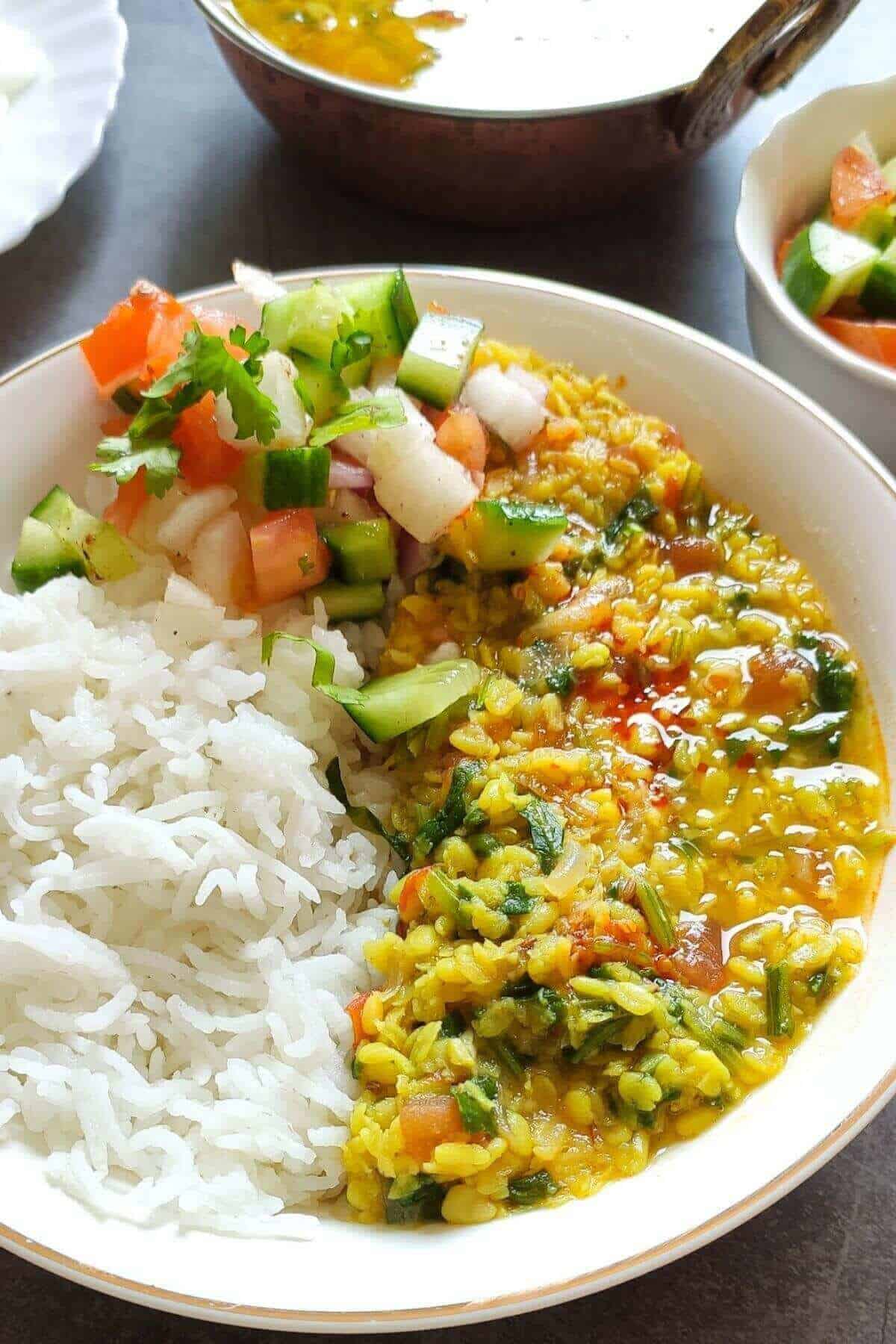 Spinach lentil curry served with rice and salad in a bowl