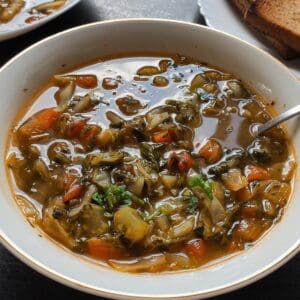 Vegan cabbage soup served in a bowl with a spoon.