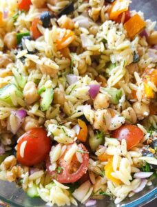 Close up shot of Greek orzo salad with chickpeas and vegetables.