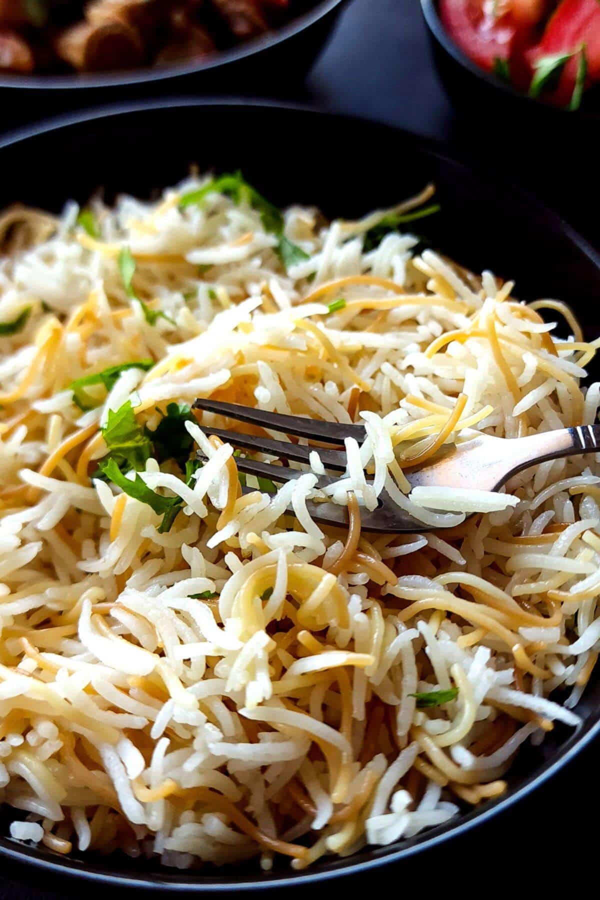 Lebanese vermicelli rice in a black bowl with a fork.