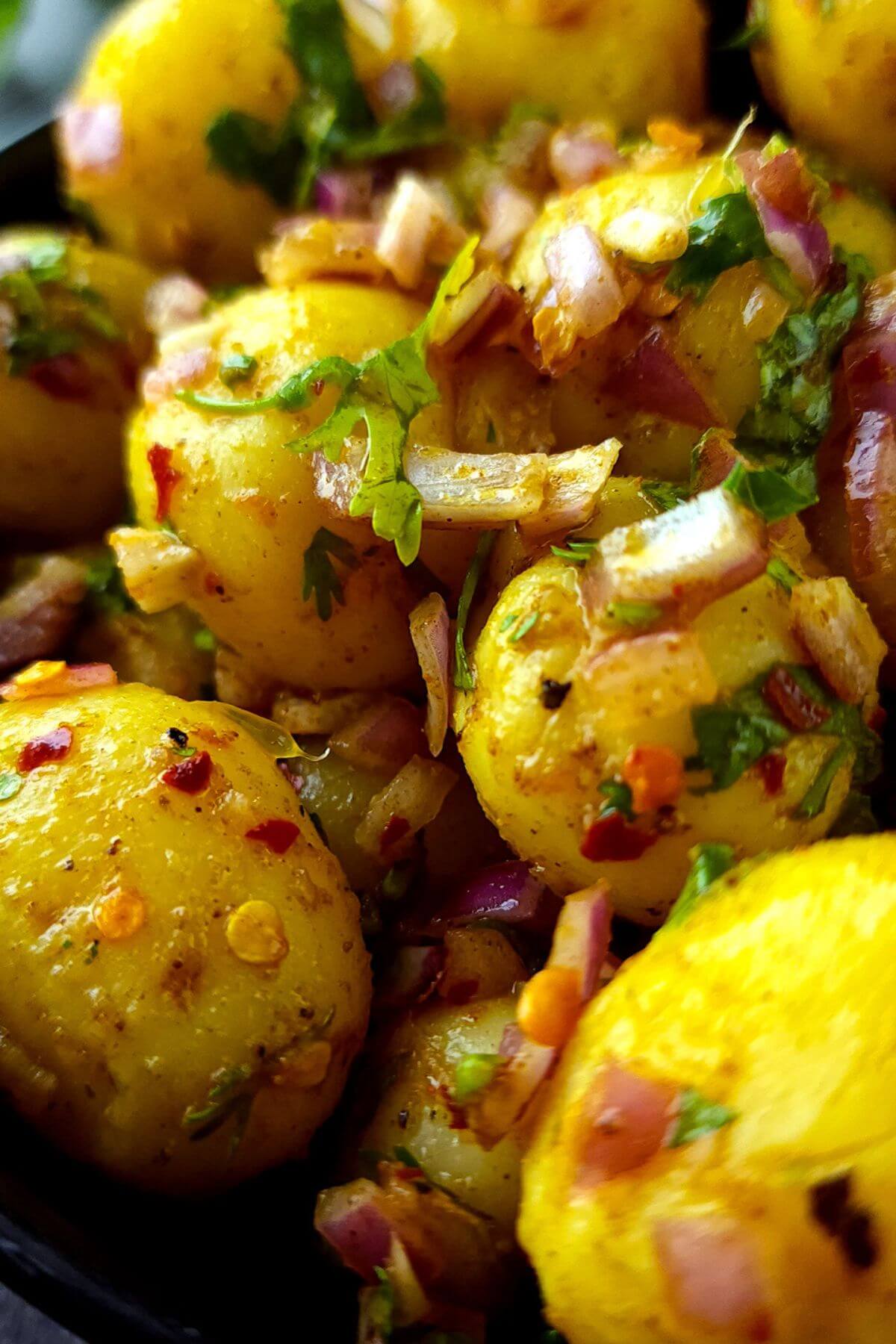 Close up shot of spicy Indian potato salad with chopped onion and cilantro.