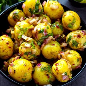 Spicy Indian potato salad in a black bowl.