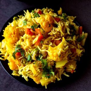 Curried rice with vegetables in a black bowl.