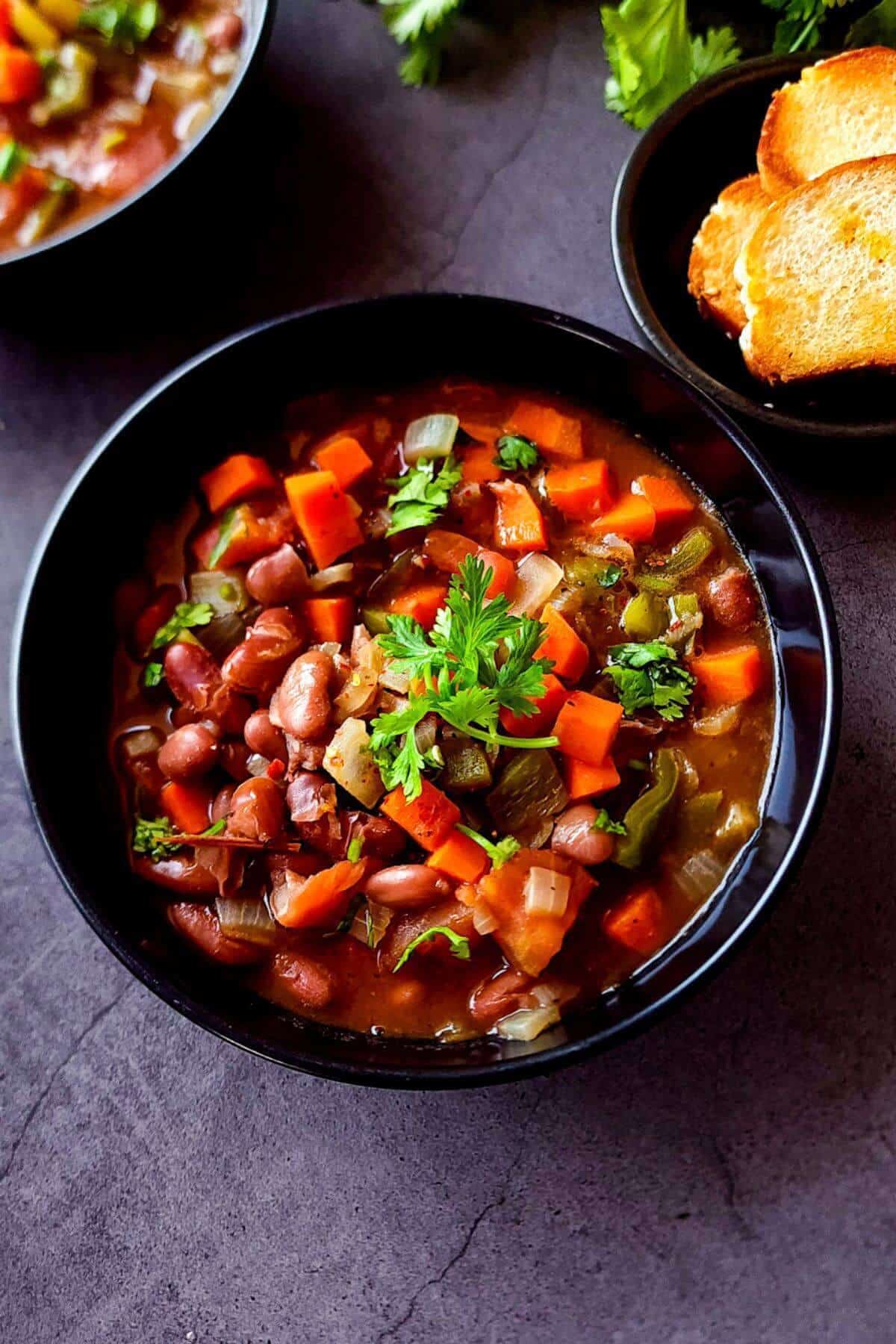 A bowl of kidney bean stew with toasted bread on the side.
