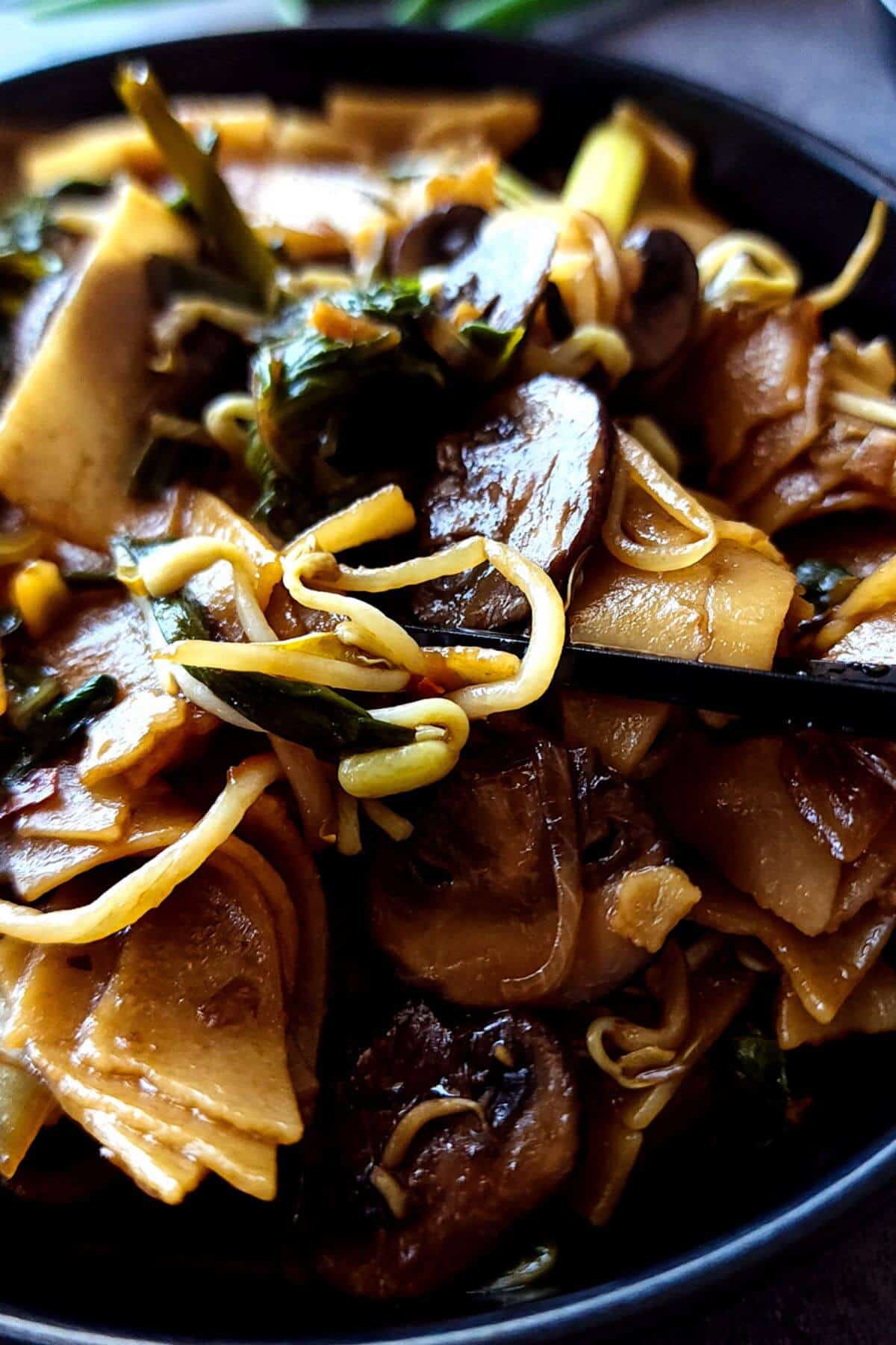 Chow fun noodles with mushrooms in a bowl.