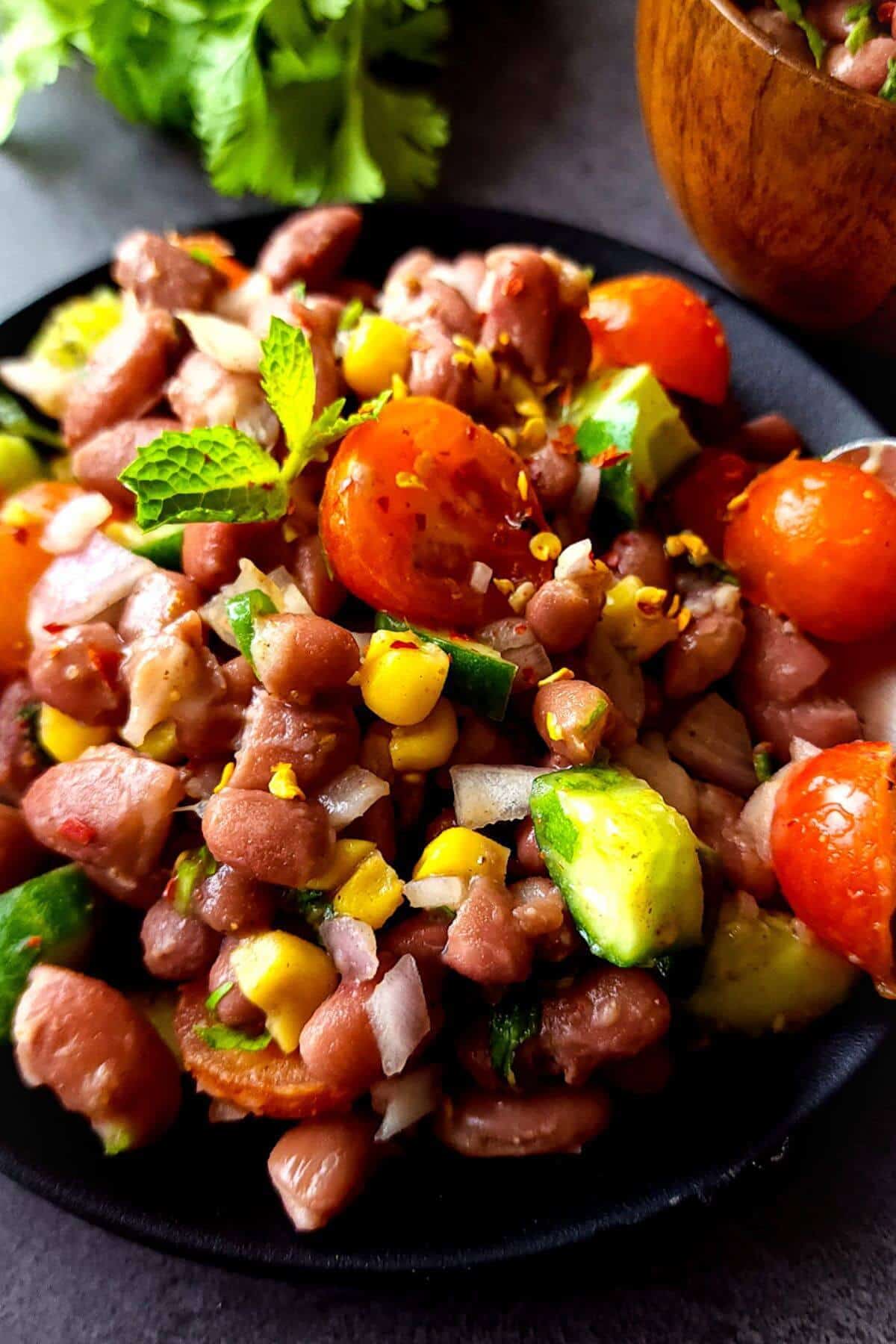 Spicy Indian kidney bean salad served on a black plate.