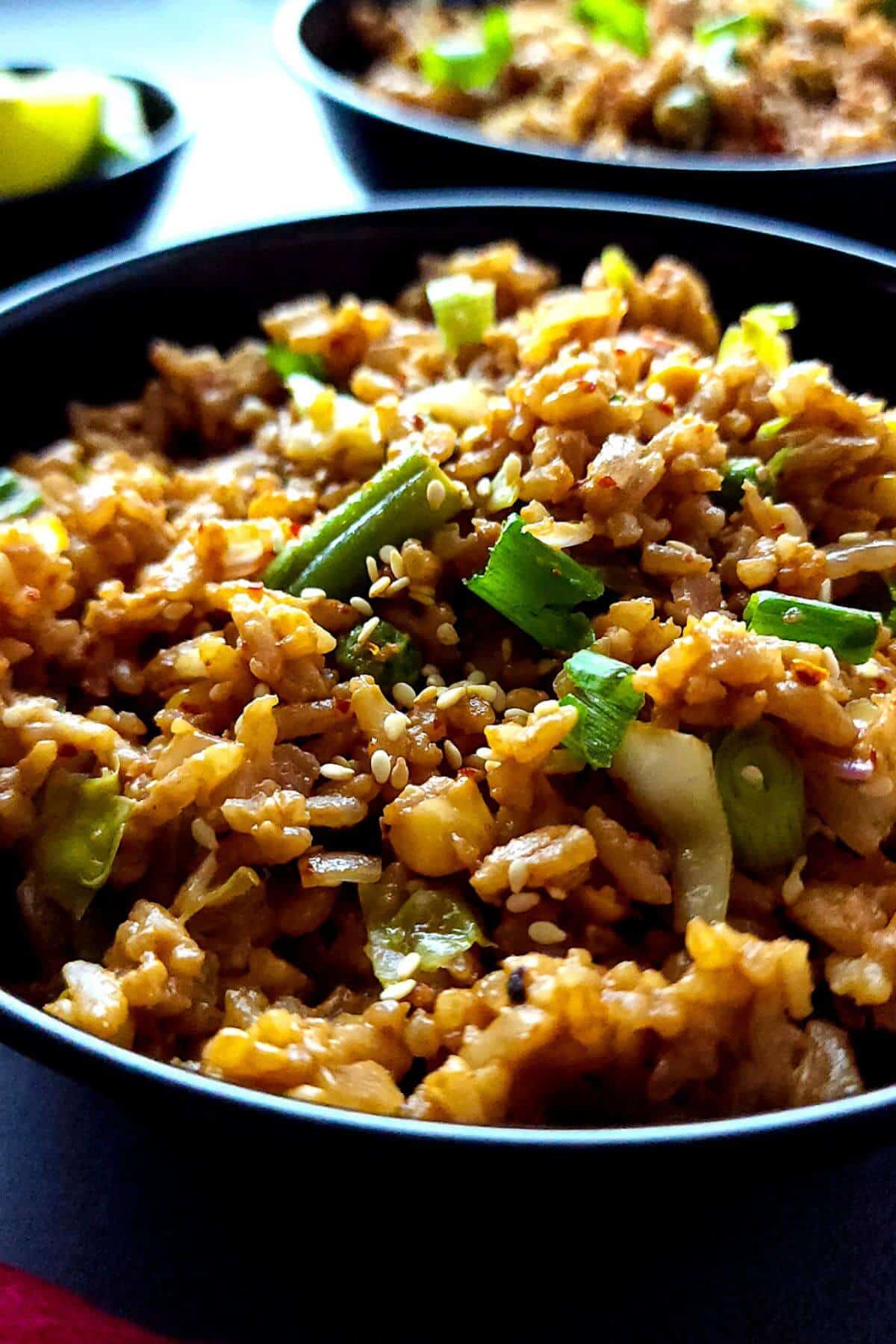 Two bowls of peanut butter rice garnished with chopped green onions.