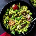 Orzo pesto pasta salad served in a black bowl with a spoon.