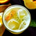A glass of orange lemonade with ice cubes.