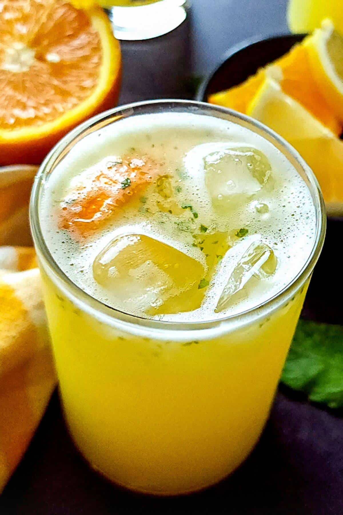 A glass of orange mint lemonade with ice cubes.