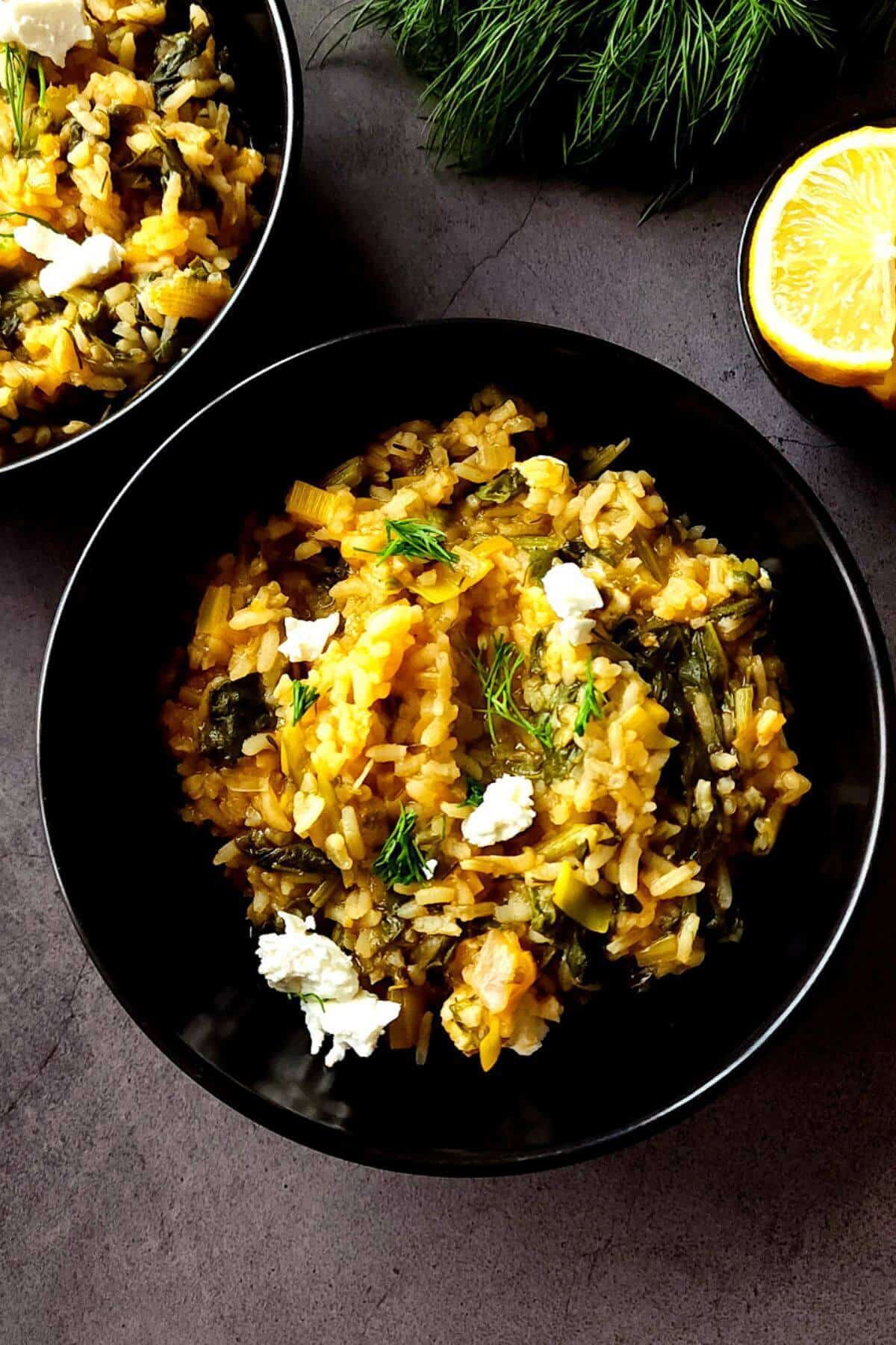 Greek rice with spinach and feta served in two black bowls.