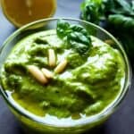 Vegan pesto garnished with pine nuts and basil leaves in a bowl.