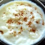 A bowl of rizogalo garnished with powdered cinnamon and lemon peel.
