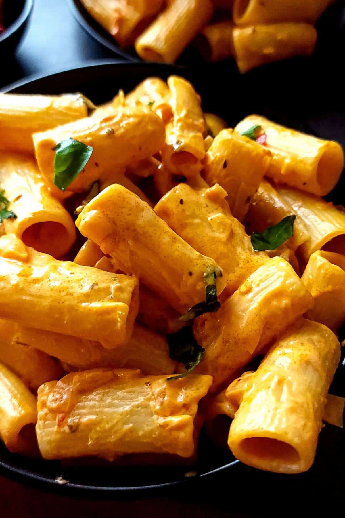 Creamy calabrian pasta served on a black plate.