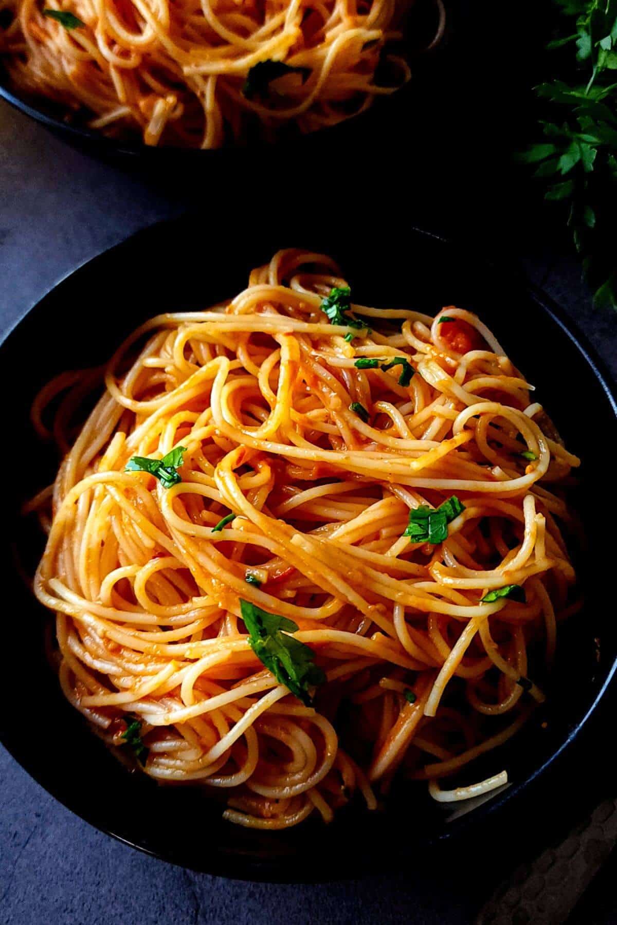 Vegan tomato spaghetti in a black bowl.