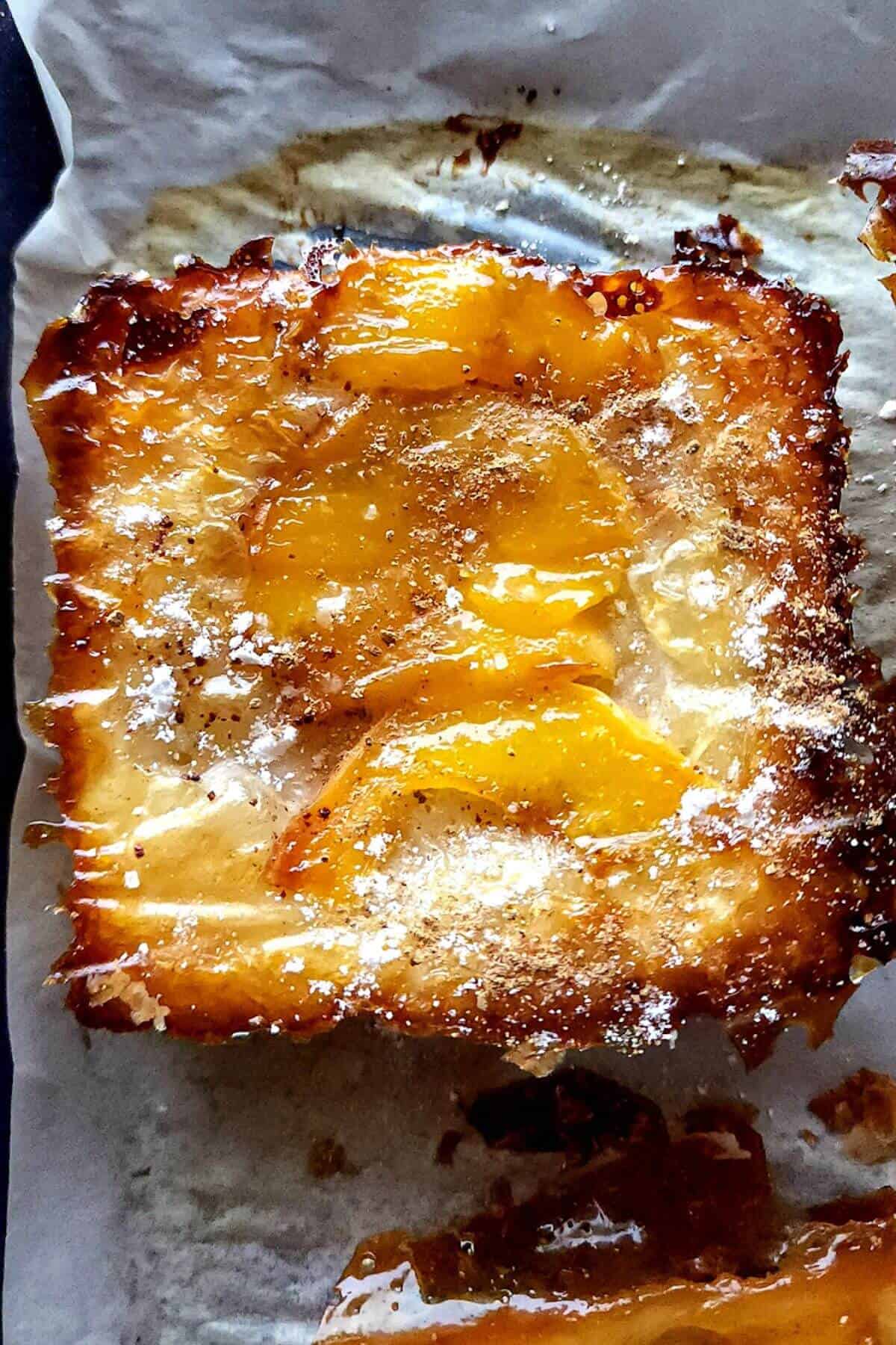Peach upside down puff pastry on a baking tray lined with a baking sheet.