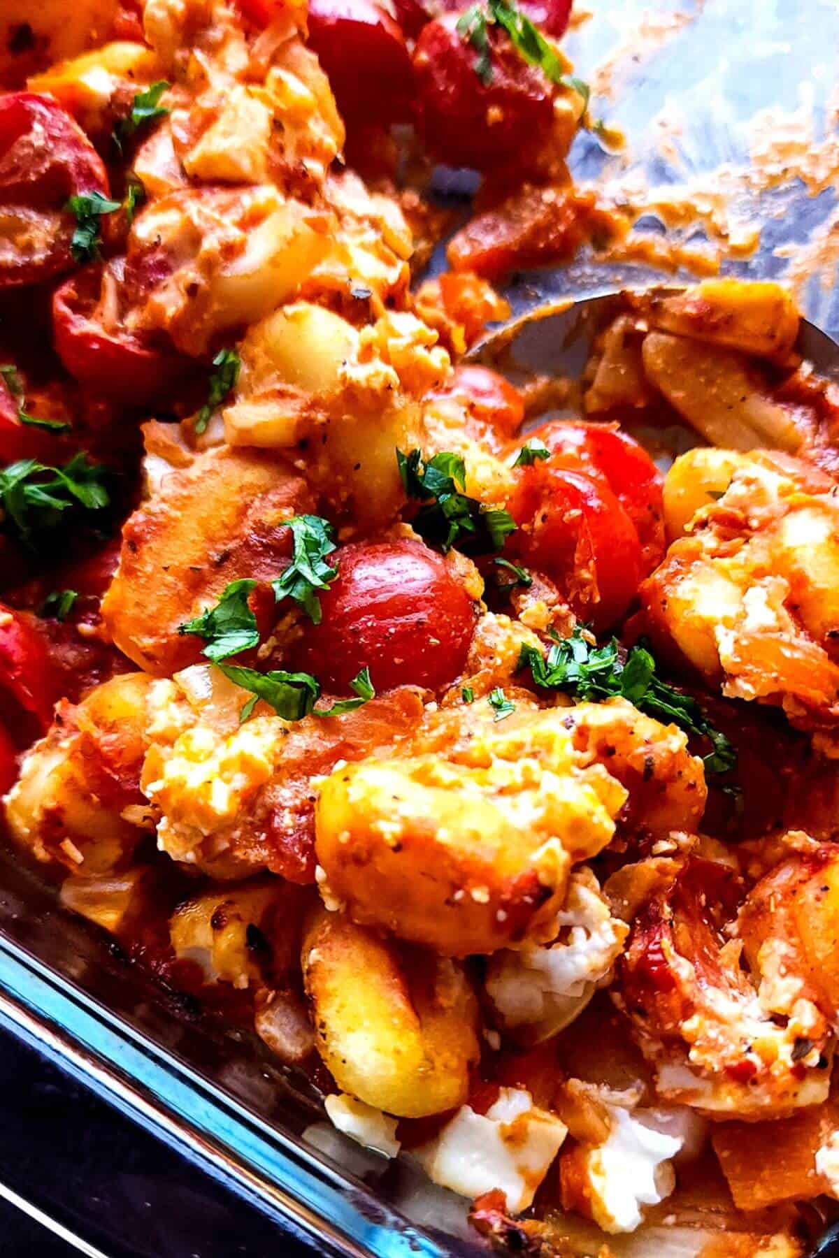 Gnocchi bake with cherry tomatoes and feta in a glass casserole.