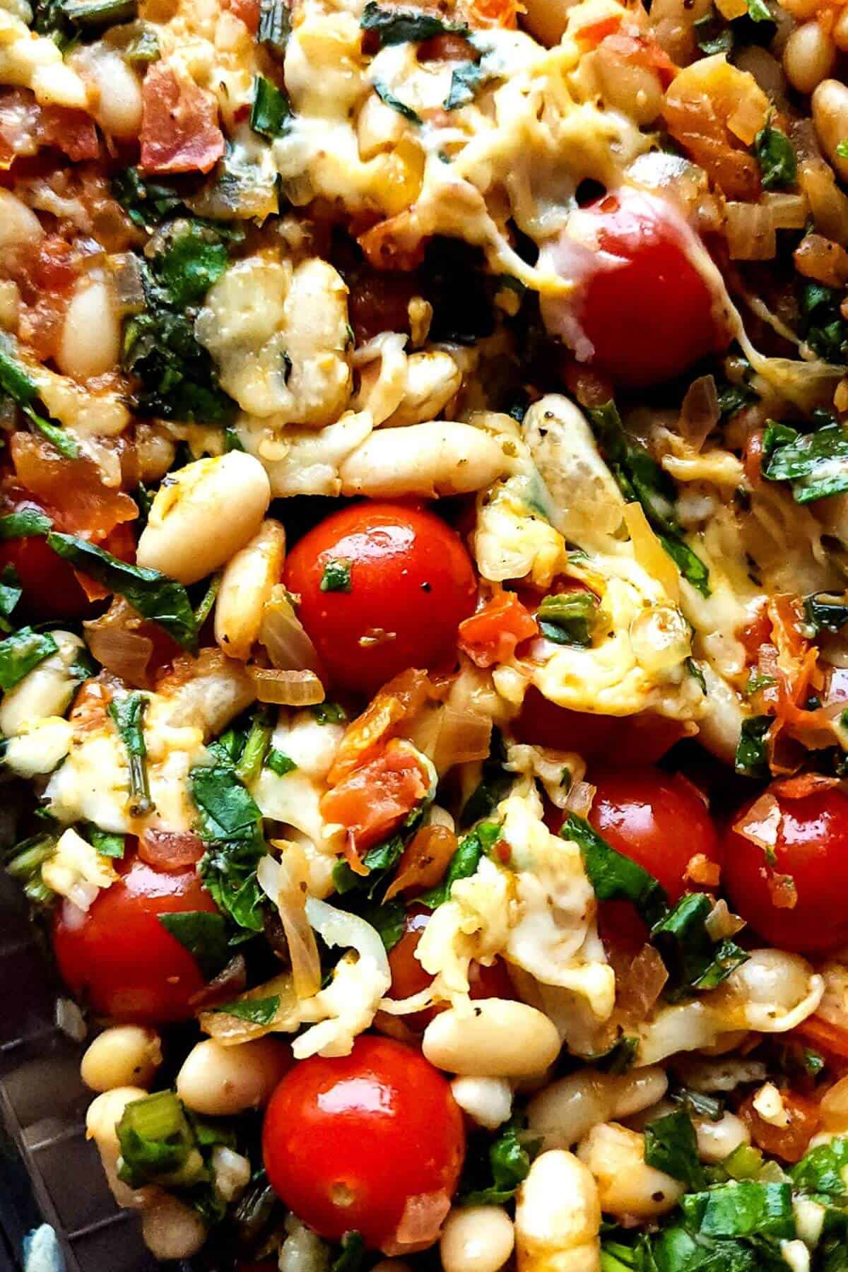 Baked white beans with spinach and cherry tomatoes.