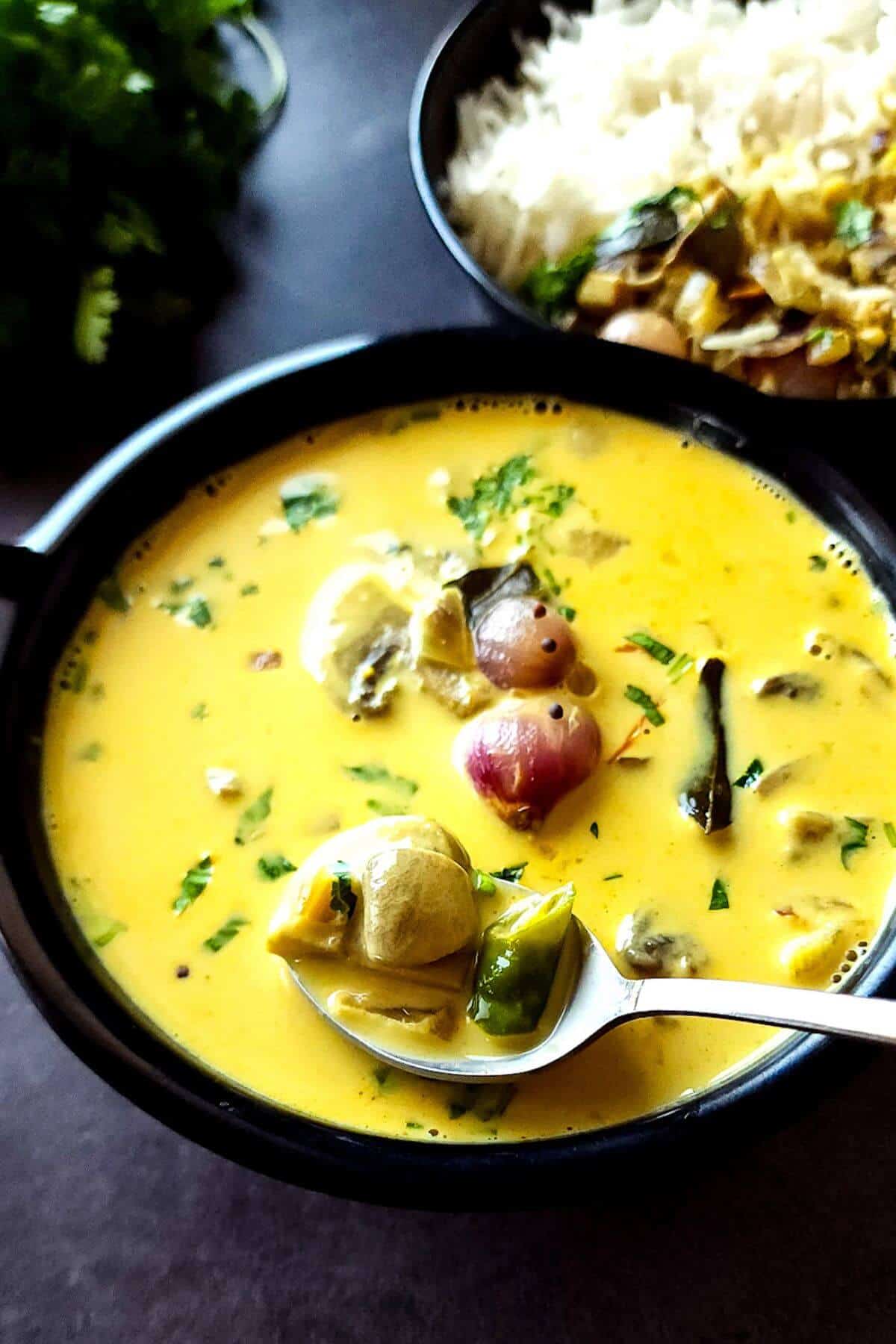 Mushroom curry with coconut milk in a bowl with a spoon.