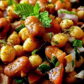 Fava bean chickpea salad garnished with mint leaves and parsley.